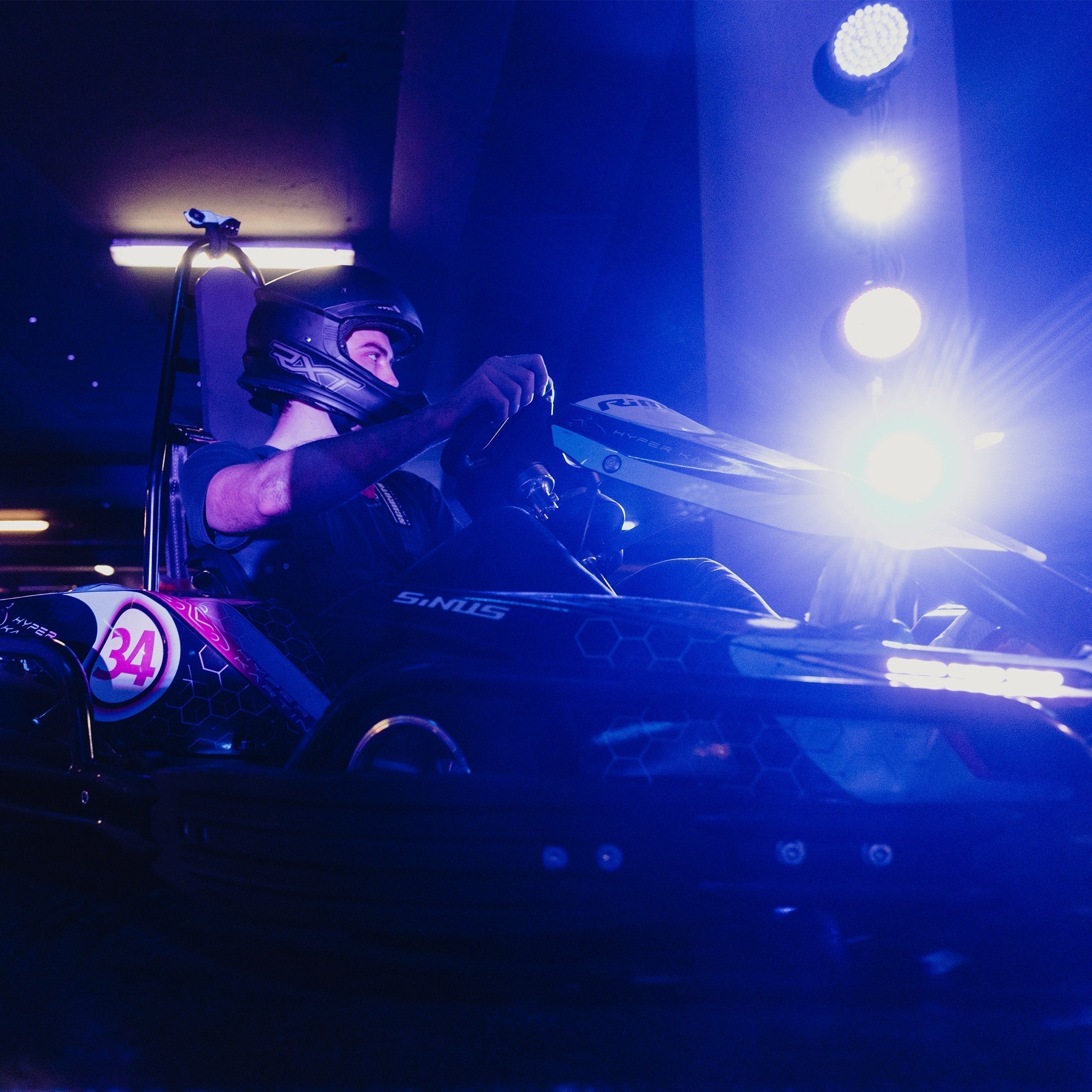Man sitting in go kart racing among lights